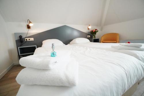 a bedroom with a large white bed with towels on it at Hotel Den Burg in Den Burg