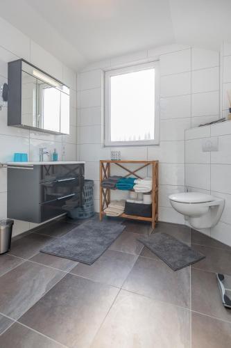 a white bathroom with a sink and a toilet at Louise am Meer in Norderney