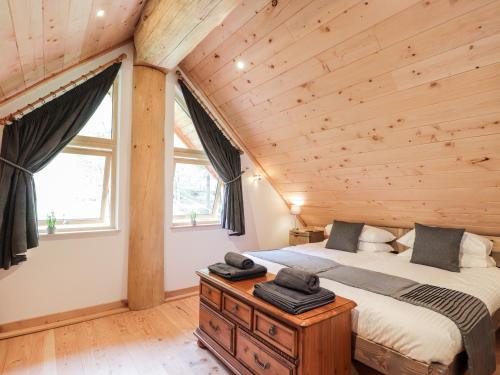 a bedroom with a bed and a wooden ceiling at Pine Marten Lodge in Grantown on Spey