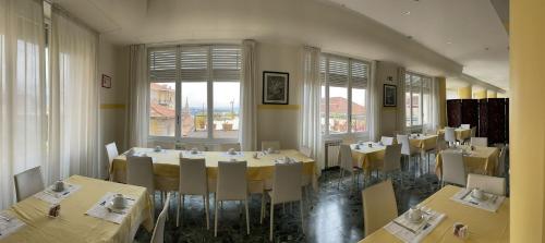 a dining room with tables and chairs and windows at Hotel Robinia in Imperia