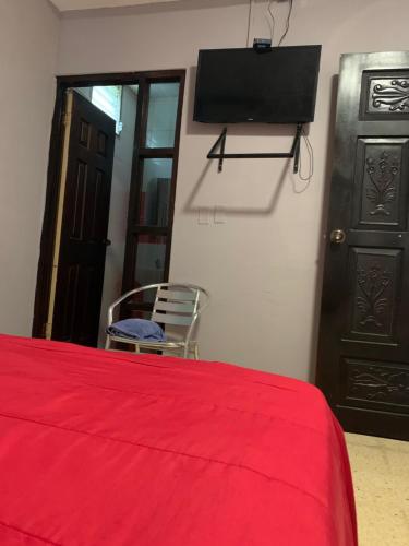 a bedroom with a red bed and a tv on the wall at Julianna Country House in Las Tablas