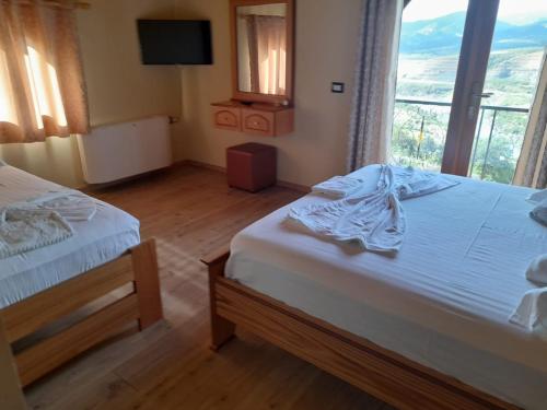 a bedroom with two beds and a large window at Bujtina Te Xhako in Përmet
