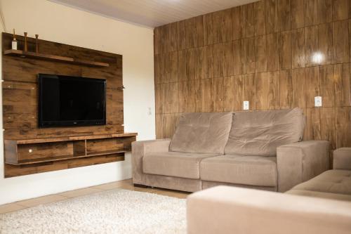 a living room with a couch and a flat screen tv at TOLEDO'S HOUSE in São Francisco de Paula