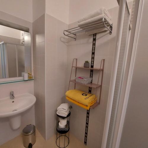 a bathroom with a sink and a shelf with towels at Villa Treccani Apartments in Malcesine