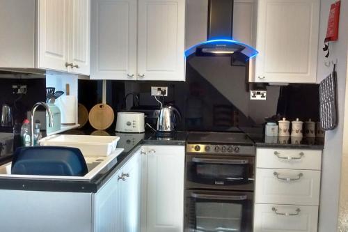 a kitchen with white cabinets and a stove top oven at Mountain Walks Straight From The Doorstep in Blaenau-Ffestiniog