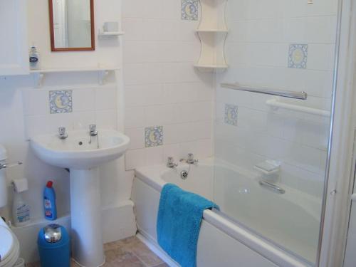 La salle de bains blanche est pourvue d'un lavabo et d'une douche. dans l'établissement Mountain Walks Straight From The Doorstep, à Blaenau Ffestiniog
