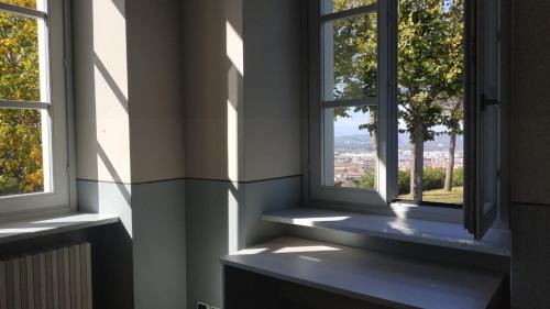 a room with two windows with a view of a city at Casa di ALTAVILLA in Alba