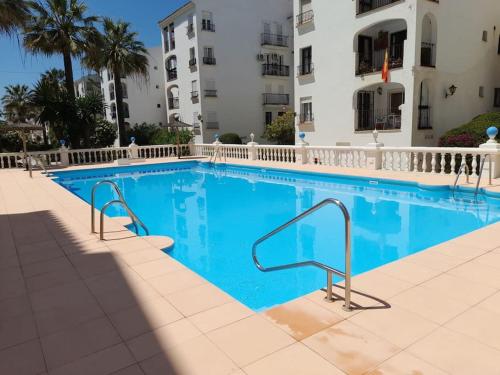 una piscina de agua azul frente a un edificio en Bonito apartamento a 50 metros de la playa., en San Luis de Sabinillas
