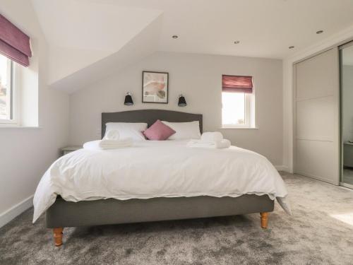 ミルソープにあるLaundry Cottageのベッドルーム1室(白いシーツとピンクの枕が備わる大型ベッド1台付)