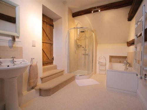 a bathroom with a shower toilet and a sink at Butlers Cottage in Burford