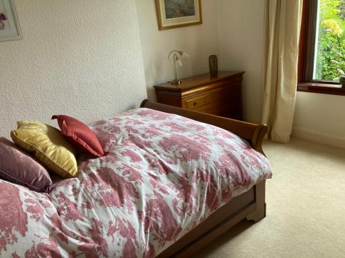 a bed with four pillows on it in a bedroom at Rose Cottage in Prestwick