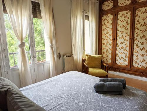a bedroom with a bed and a chair and windows at Living Plaza de la Paja in Madrid