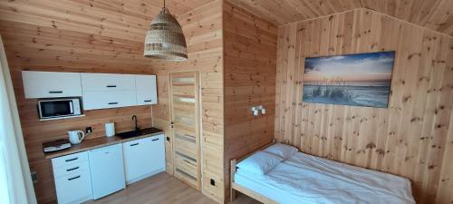a kitchen with wooden walls and a bed in a room at Gemini MiniDomki in Ustka