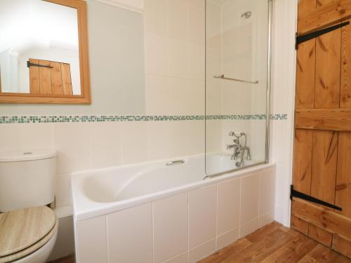 a bathroom with a tub and a toilet at Hedgehog Cottage in Minehead