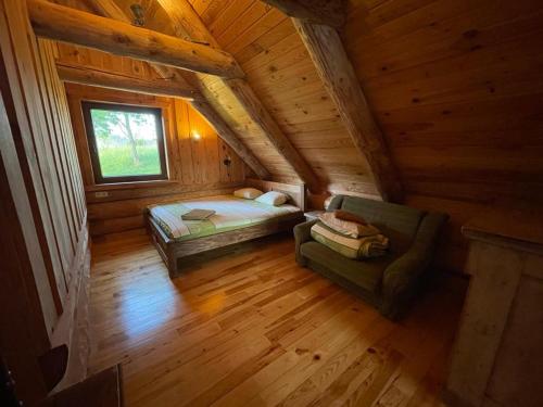 ein Zimmer mit einem Bett und einem Sofa in einer Hütte in der Unterkunft Vucini in Andzeļi