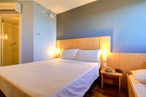 a bedroom with a large white bed and a blue wall at ibis Vitoria Praia de Camburi in Vitória