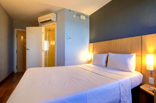 a bedroom with a large white bed with a blue wall at ibis Vitoria Praia de Camburi in Vitória