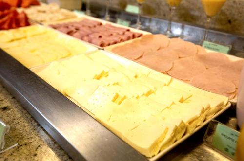 a tray of cheese on a counter with other foods at ibis Vitoria Praia de Camburi in Vitória