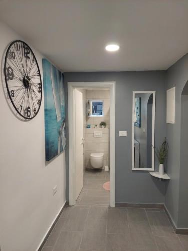 - un couloir avec une salle de bains pourvue d'une horloge murale dans l'établissement Apartman Karla, à Jadrija