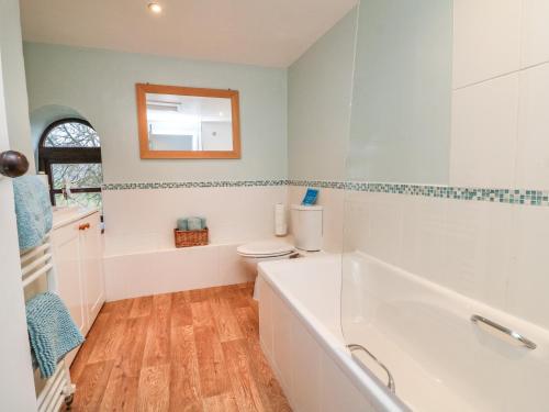 a bathroom with a tub and a toilet and a mirror at Barn Owl Cottage in Minehead