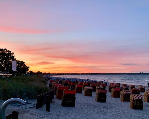 a group of chairs on the beach at sunset at Ferienwohnung Beachhus in Scharbeutz