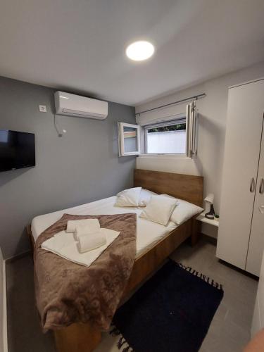 een kleine slaapkamer met een bed en een raam bij Apartman Karla in Jadrija