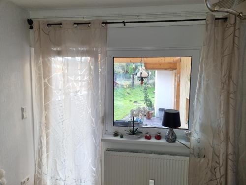 ein Fenster mit einem weißen Vorhang in einem Zimmer in der Unterkunft Fewo-Kreiensen in Einbeck