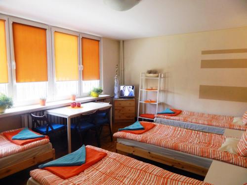 a room with three beds and a table and a refrigerator at Lama Rooms in Warsaw