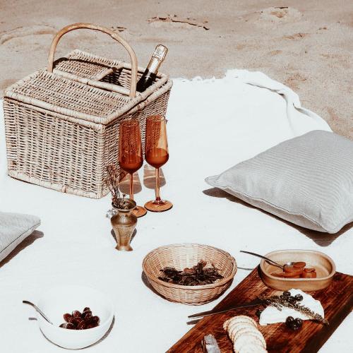 a table with a basket and two glasses and food at Stanley Island in Plettenberg Bay