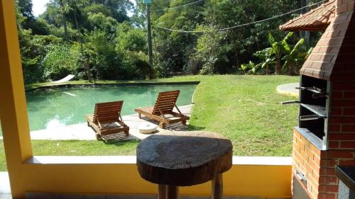 a view of a pool with two chairs and a table at Sitio Espelho Dagua - Brotas SP in Brotas