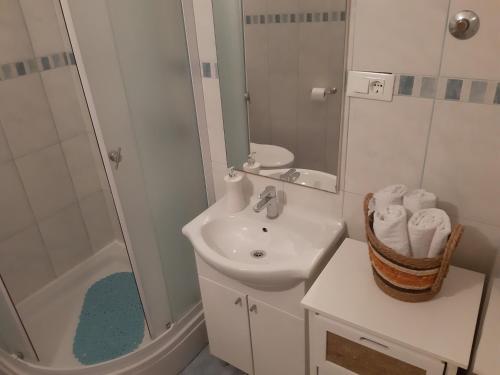 a white bathroom with a sink and a shower at Apartments Knežić in Igrane