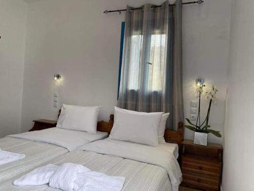 a bedroom with two beds with white sheets and a window at LUNAR MELODY in Karpathos