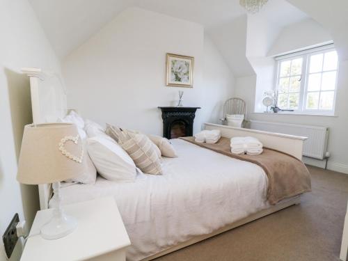 a bedroom with a large white bed and a fireplace at 5 Pond View Cottages in Brough