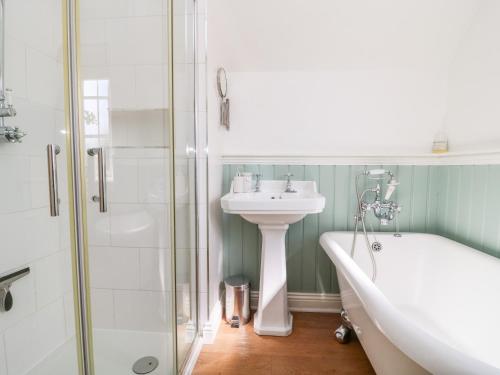 La salle de bains est pourvue d'une baignoire, d'un lavabo et d'une douche. dans l'établissement 5 Pond View Cottages, à Brough