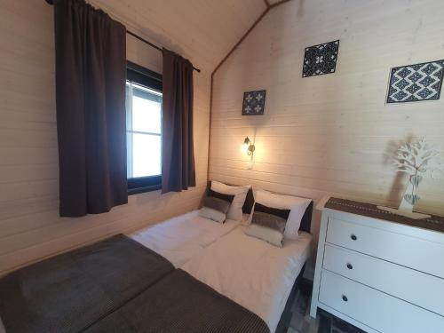 niewielka sypialnia z łóżkiem i oknem w obiekcie Domki Apartamenty Retro w mieście Jarosławiec