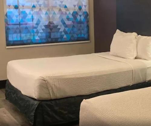 two beds in a bedroom with a painting on the wall at La Quinta Inn by Wyndham Bakersfield South in Bakersfield