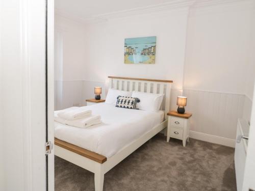 a bedroom with a white bed and a mirror at Bodnant in Llandudno