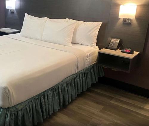 a bed in a hotel room with a phone on a table at La Quinta Inn by Wyndham Bakersfield South in Bakersfield