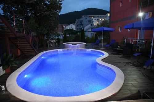 una gran piscina en el patio trasero por la noche en VilaElenaMarko en Budva