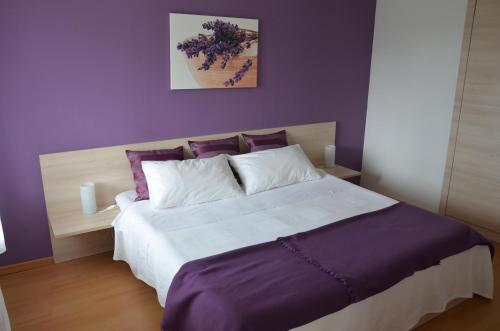 ein Schlafzimmer mit einem großen Bett mit lila Wänden in der Unterkunft Apartments Ostanek in Portorož