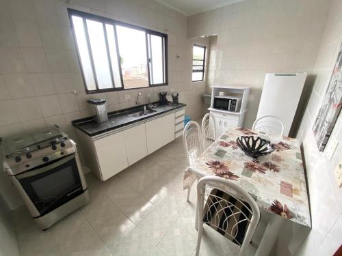 a kitchen with a table and a stove and refrigerator at Apartamento no Guarujá, a poucos minutos da praia in Guarujá