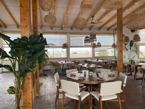 uma sala de jantar com mesas, cadeiras e janelas em DEL REY em Paralia Katerinis