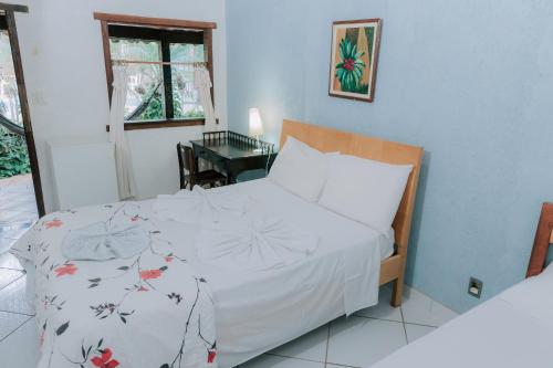 a bedroom with a bed with a white comforter at Pousada Adega Cipo in Serra do Cipo
