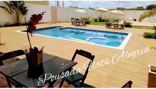 a table with a flower on it next to a swimming pool at Pousada Flats Alegria in Olímpia