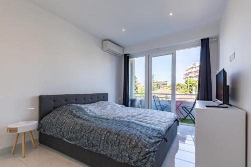 een slaapkamer met een bed, een televisie en een balkon bij BNB Renting one bedroom apt completely renovated behind the Martinez hotel in Cannes