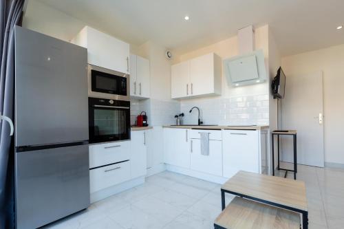 une cuisine avec des armoires blanches et un réfrigérateur en acier inoxydable dans l'établissement Le Cirodde one bedroom apt completely renovated behind the Martinez hotel, à Cannes