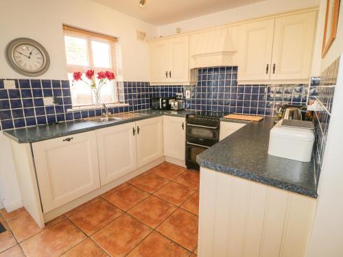 a kitchen with white cabinets and a tile floor at 1 Closheen Lane in Rosscarbery