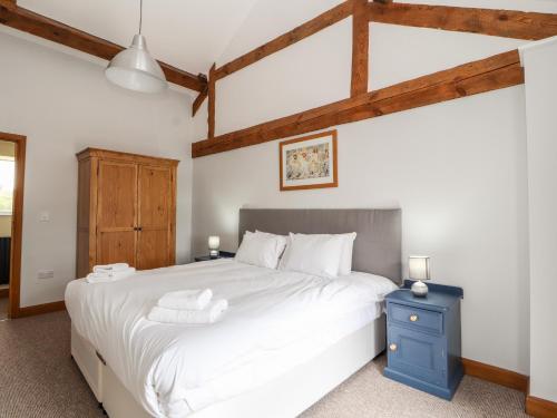 um quarto com uma grande cama branca e uma mesa de cabeceira azul em The Cart House em Whitchurch