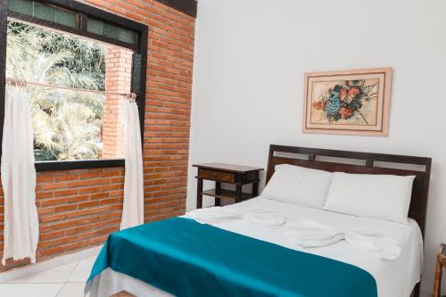 a bedroom with a bed and a brick wall at Pousada Adega Cipo in Serra do Cipo