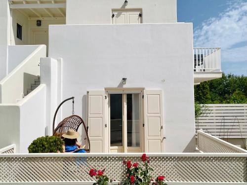 a woman sitting in a chair on the balcony of a house at Sorokos Suite 8 in Naxos Chora